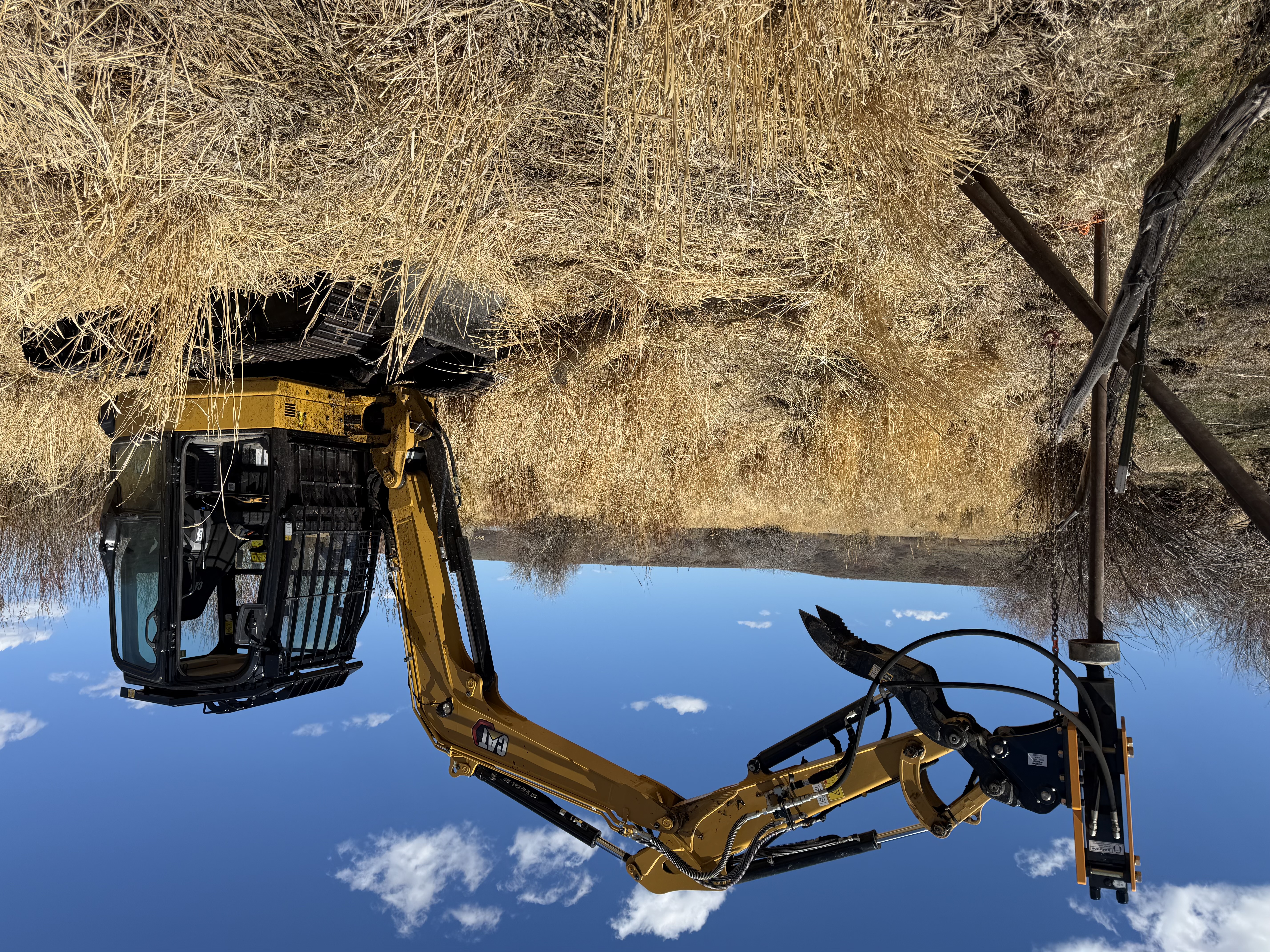 Operator using a skid steer post driver for fence installation